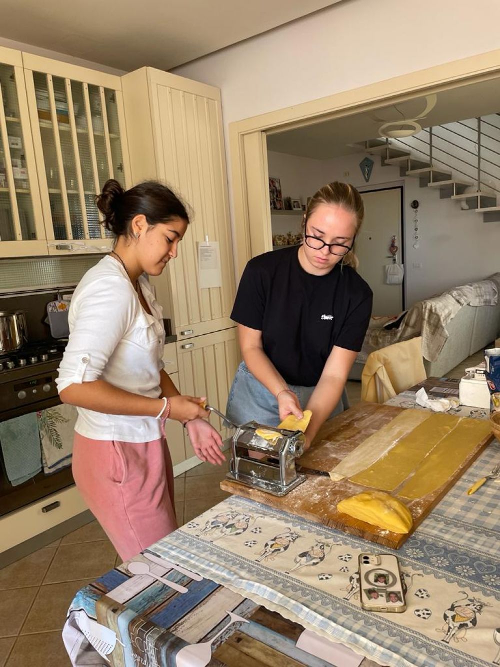 Alojando a un estudiante en tu casa - la hermana anfitriona compartiendo una receta de pasta con el estudiante de intercambio